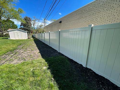 A solid white PVC fence along the back of a large business