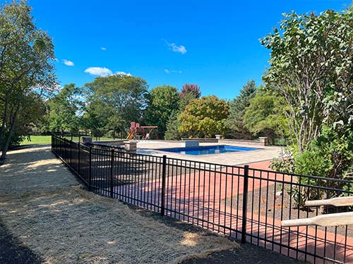 A black aluminum fence surrounding a pool at a home