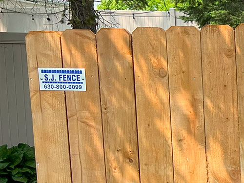 close up of the SJ Fence sign on a wood fence